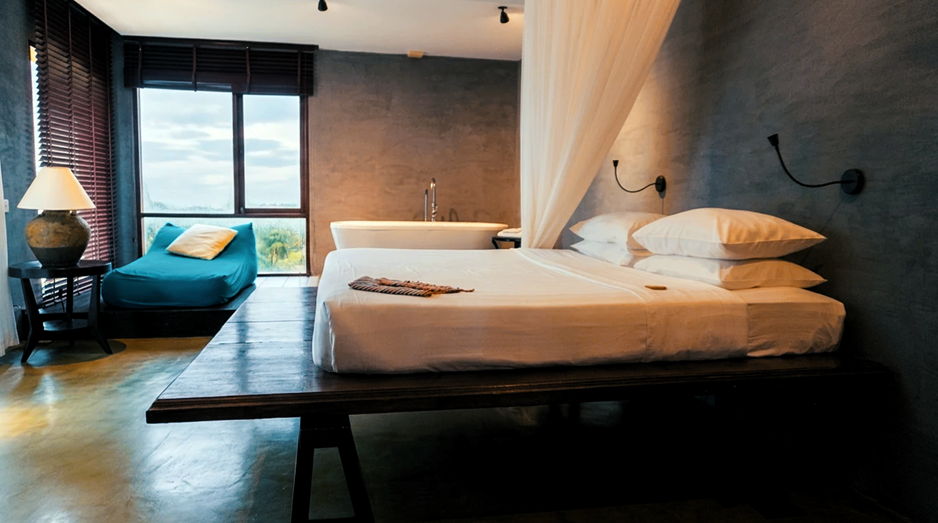 A moody, sea-facing suite — freestanding bathtub, canopy bed, and uninterrupted horizon
