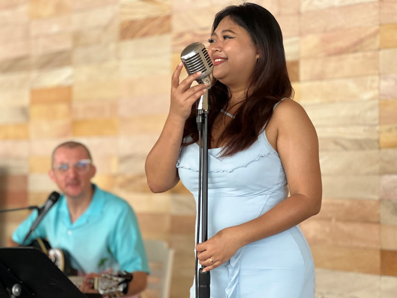 Melody Mouyseang and Joe Wrigley on stage, vintage mic and guitar in hand