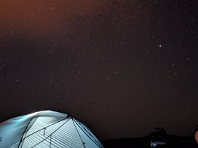 A tent under the milky way. The stars are clearly visible.