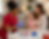 A phlebotomist in scrubs draws blood from a child seated on her mother’s lap, providing comfort during an in‑home blood draw.