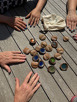 Multiple hands gathered around wooden table with colorful game tokens.