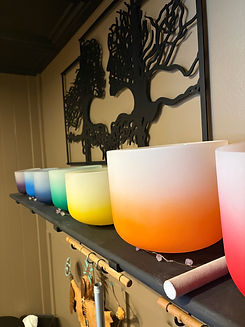 closeup of crystal bowls on a shelf under a metal sculpture of the tree of life