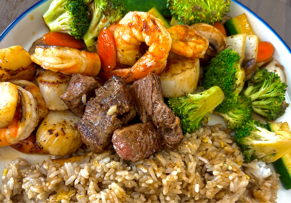 Plate of shrimp, beef, broccoli, and fried rice, colorful and glossy on a white-rimmed dish.
