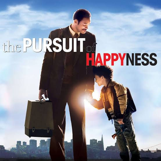 Man and child standing, holding hands; man's carrying a briefcase. City skyline backdrop. Text reads "the Pursuit of Happiness." Warm mood.