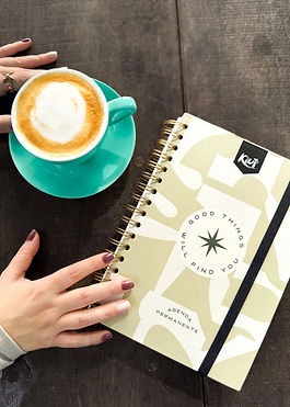 foto en plano cenital de una agenda y un café sobre mesa de madera