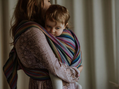 Parent carrying a newborn in a woven wrap tied securely