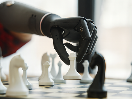 Human and robotic hands playing chess, representing collaboration between people and AI.