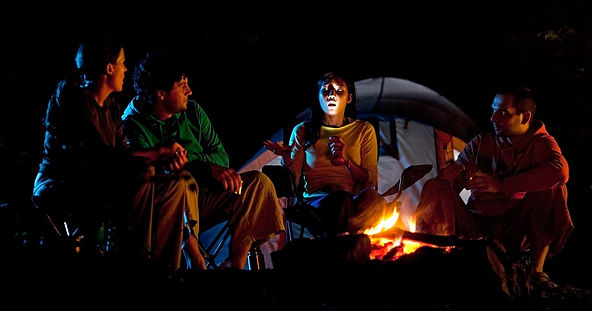 Four friends sitting around the campfire and telling scary stories as alternatives to trick or treating