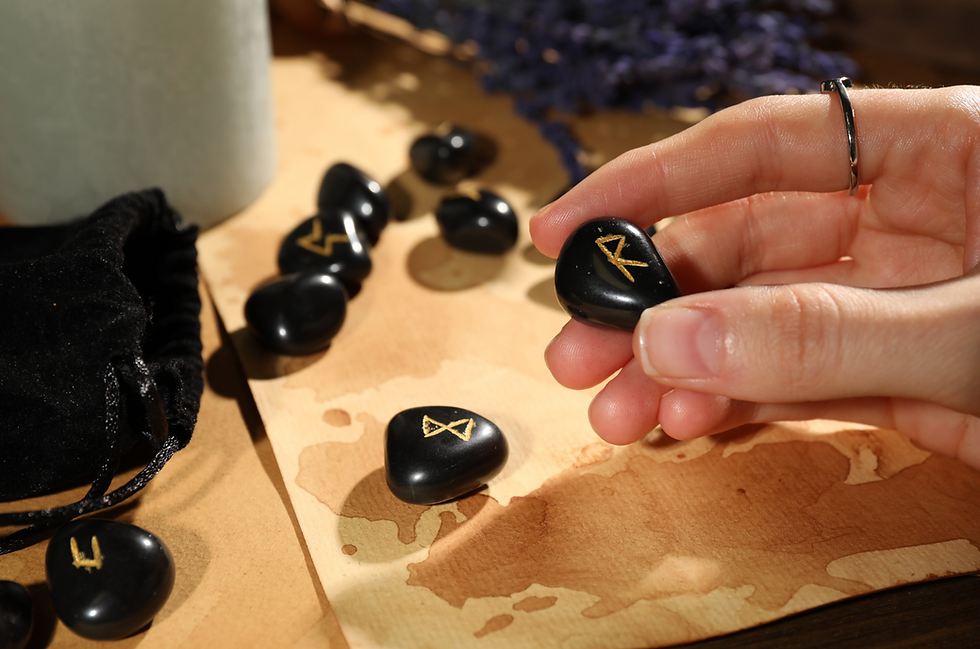 Hand holding rune stone with Raidō symbol (ᚱ) during divination on wooden table