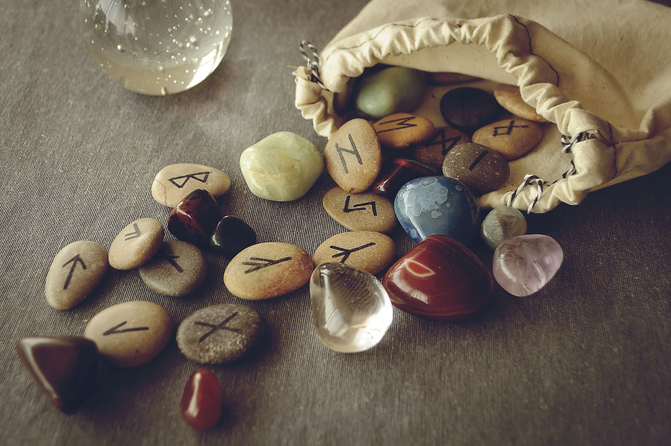 Rune stones with Elder Futhark signs spilling from a linen pouch among polished crystals