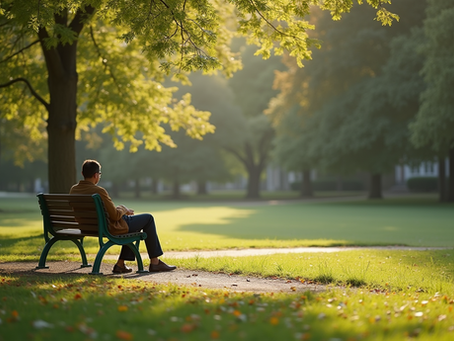 A man sitting alone on a peaceful Park bench in a park.