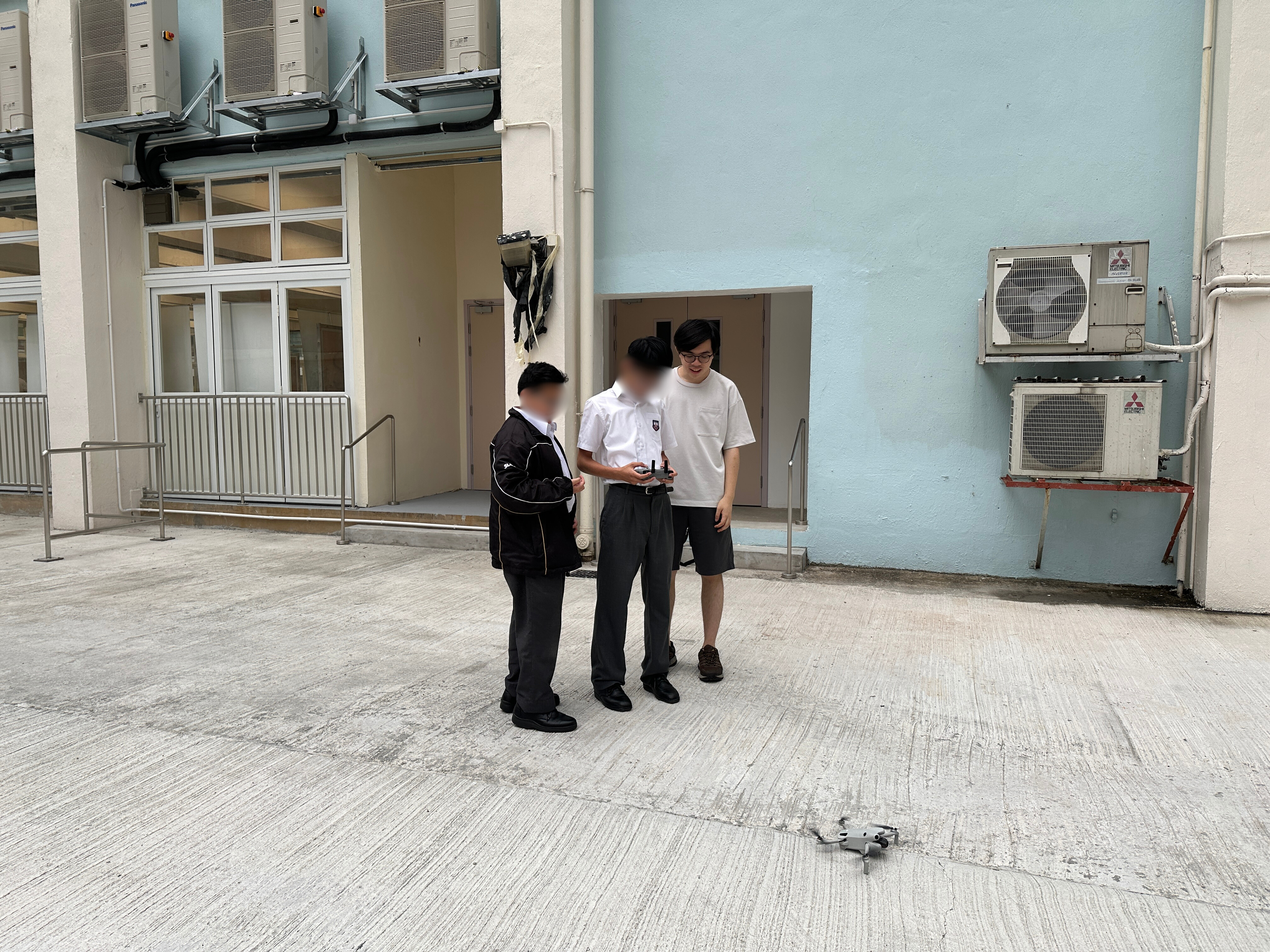 一名導師正在指導兩位學員操控小型無人機