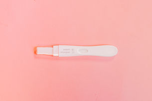 A white pregnancy test on a pink background.
