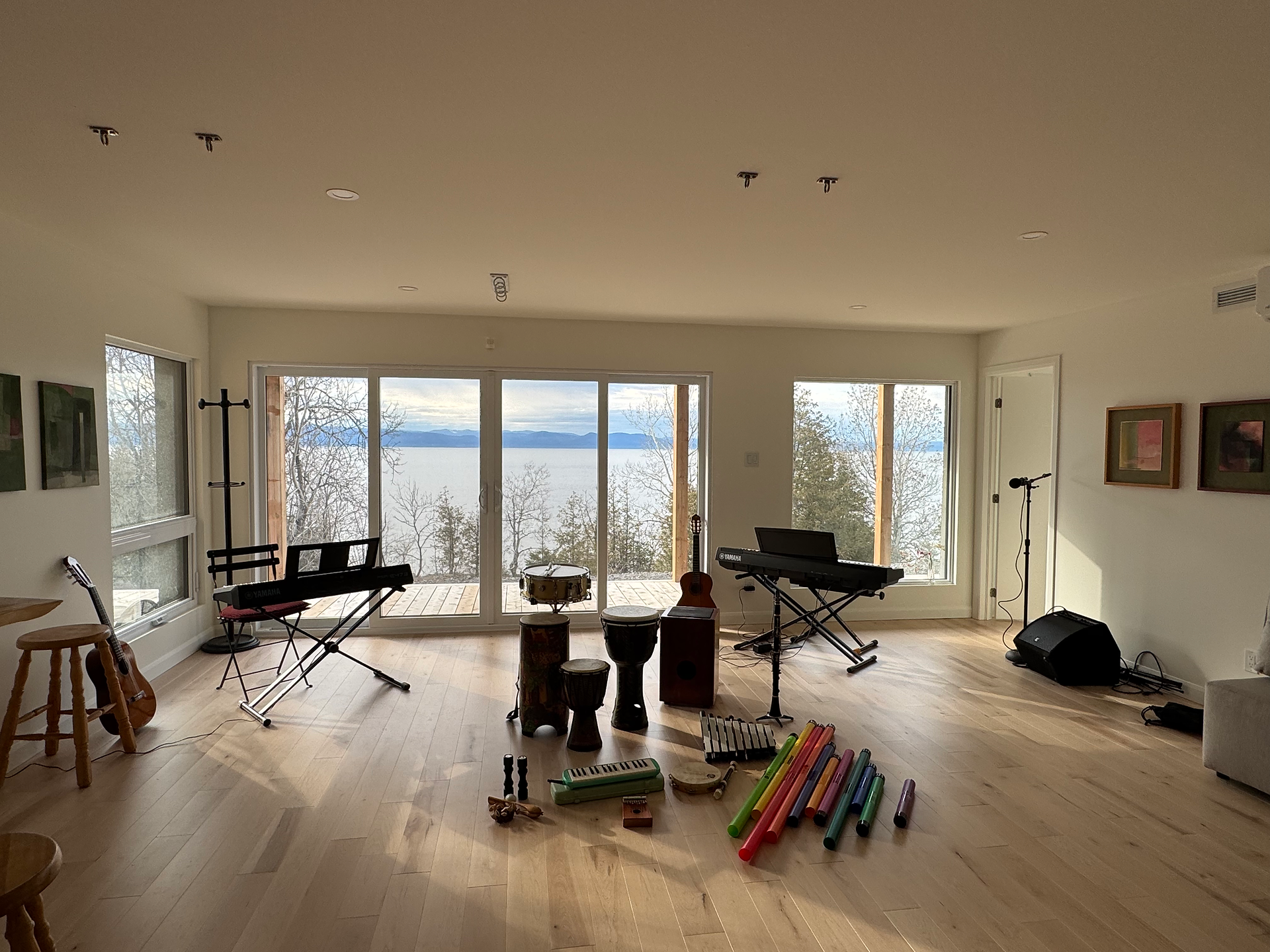 A room with tall windows, filled with musical instruments gathered in the center.