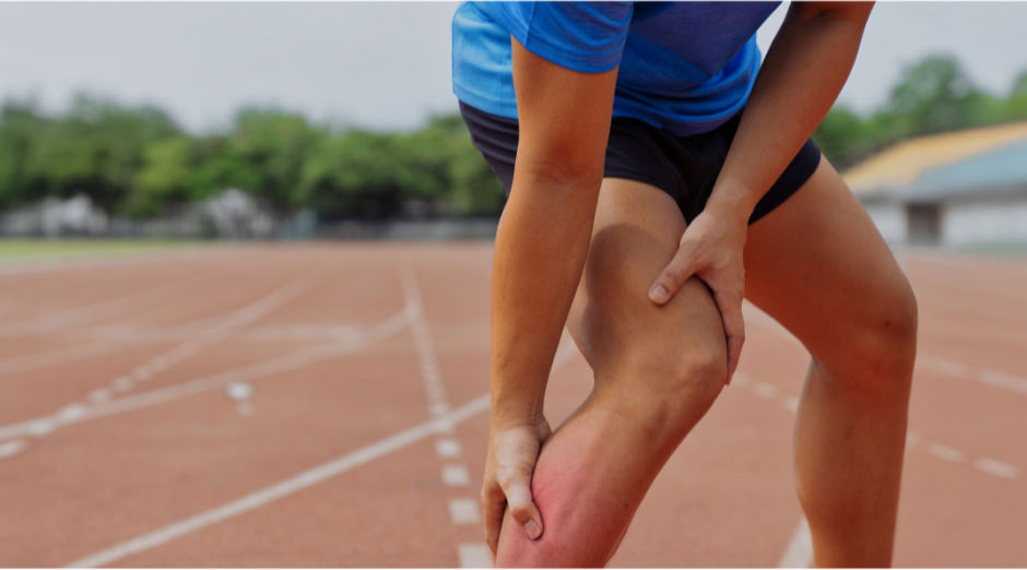 Personne se tenant la cuisse sur une piste d’athlétisme suite à une crampe musculaire