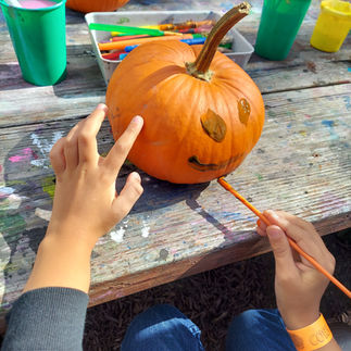 a child painting a face on a pumpkin at Corn Cob acres fall event