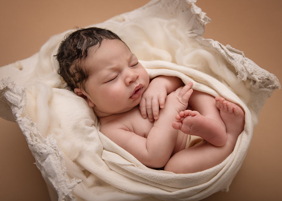 Newborn baby sleeping peacefully, wrapped in a soft cream blanket on a beige background, exuding warmth and serenity.