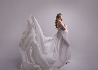 silhouette of pregnant woman, she is draped in white fabric and it is flowing behind her