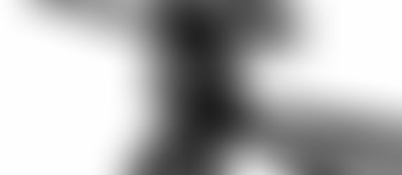 Pregnant woman poses for maternity portraits draped in black fabric against a white backdrop with one hand on the small of her back and the other on the top of her head with her hair flowing behind her