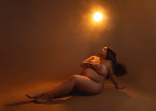 a maternity portrait of a woman, her silhouette is outlined with orange glowing light