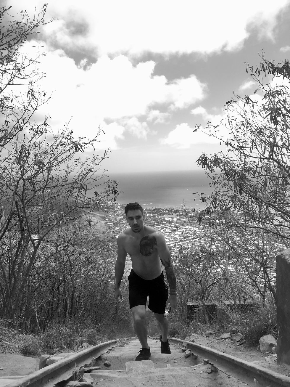 Well muscled man climbing his way to the top of a mountain at the end of a long hike for fitness