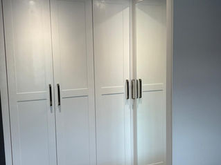 A bespoke white corner wardrobe with mirrored door