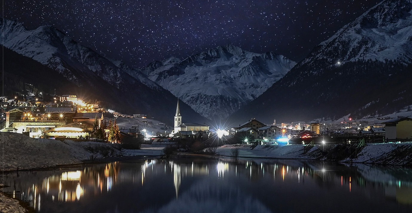 Night view of Livigno with its lake, snow-capped mountains, and starry sky – La Sorgente Apartments
