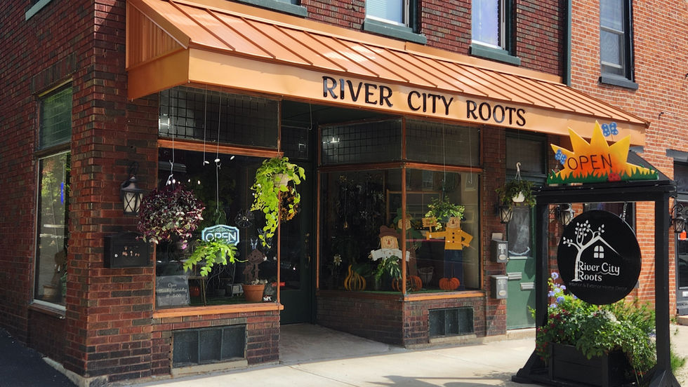 River City Roots plant and home décor shop in downtown Aurora, Indiana, with a copper awning, hanging plants and fall window displays