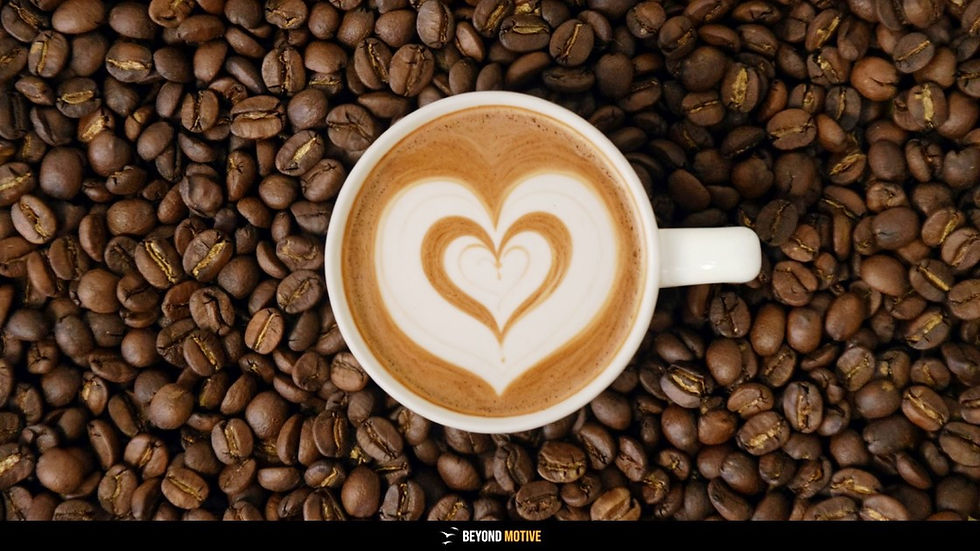 A cup of coffee with heart-shaped latte art sits on a bed of coffee beans. Warm brown tones and a soothing ambiance. Text: "BEYOND MOTIVE."