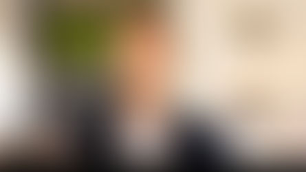 Smiling man in a suit in a bright, modern setting with plants and lights. Text "Beyond Motive" below. Warm, welcoming atmosphere. 10 Proven Ways to Overcome Fear and Build Lasting Courage