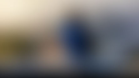 A person with a backpack sits on rocky terrain, overlooking a scenic mountain and water view at sunset. Peaceful and contemplative mood. How Reconnecting with Nature Can Improve Your Well-Being.