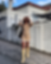 Girl in orange and white dress, sunnies, and yellow boots walking down the road.