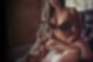 Man in bed taking photo of woman from his phone, who is sitting on top of him