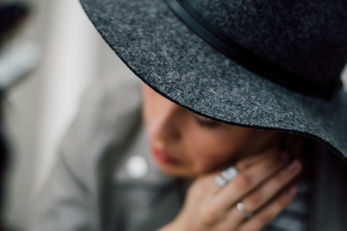 Woman wearing gray felt hat and rings