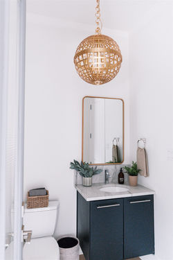 Bathroom design featuring floating vanity, wood framed mirror, brass light fixture and acc