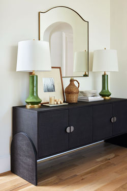 Breakfast nook design with black grasscloth sideboard with brass mirror and green lamps by