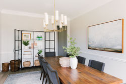Dining room design with white linen drapes, brass chandelier, wood dining table, gray dini