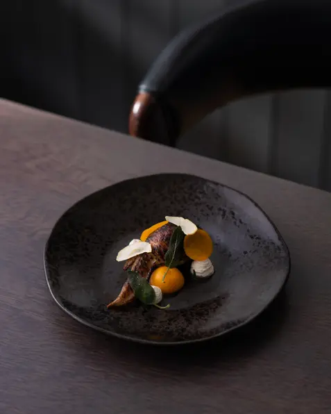 Fine dining presentation of a chicken wing in a restaurant setting. Professional food photography using natural light for an authentic in situ feel by Patryk Majewski at Patryk Creative.