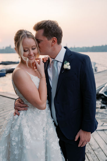 bride and groom snuggle at sunset on the dock of Royal Lake of the Woods Yacht Club