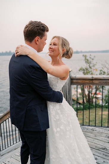 bride and groom snuggle at sunset on the dock of Royal Lake of the Woods Yacht Club