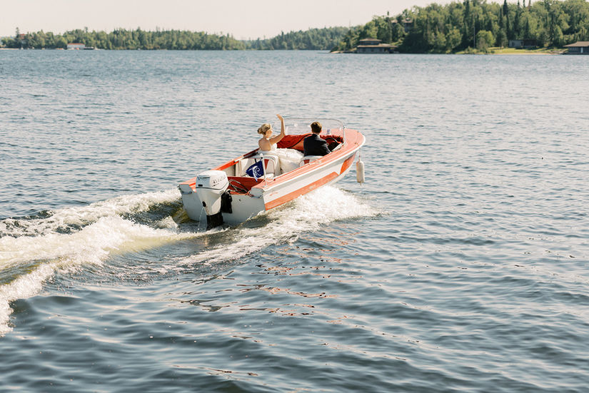 The bride and groom boat over to Royal Lake of The Woods Yacht Club
