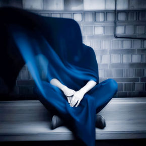 An unidentified figure wrapped in a blue shroud that fades to black