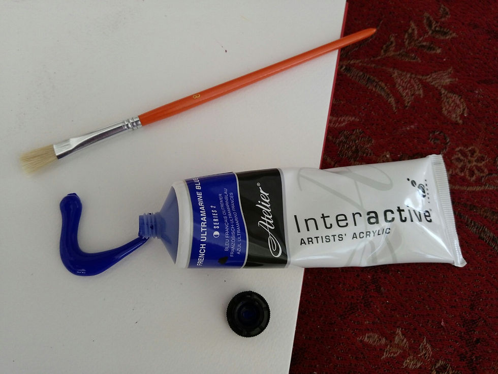 A photograph of a paint brush, sketch pad, and blue paint coming out of the tube.