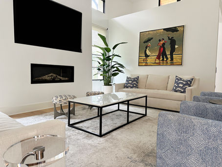 Living room designed by R. Frierson Interiors with a sculptural fireplace, ocean-toned club chairs, and hand embroidered stools