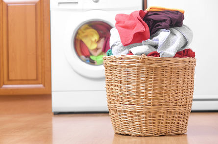 photo of a basket full of laundry by the washer and dryer.