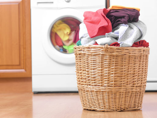 photo of a basket full of laundry by the washer and dryer.
