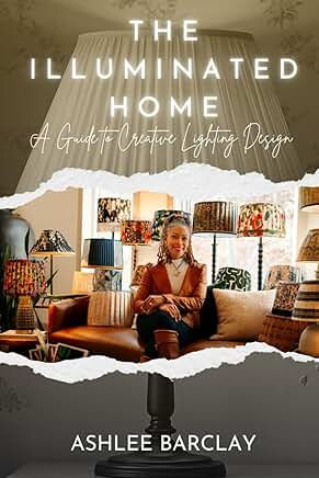 Book cover for The Illuminated Home by Ashlee Barclay, showing a woman seated in a cozy lamp-filled living room.