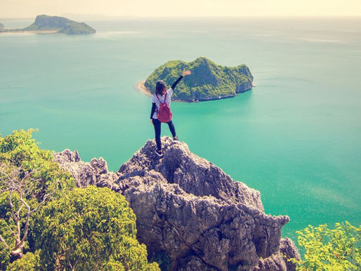Photo of a woman standing on a mountain overlooking the ocean