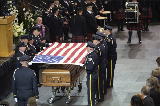 Police officers folding a US flag over the coffin of a fallen comrade