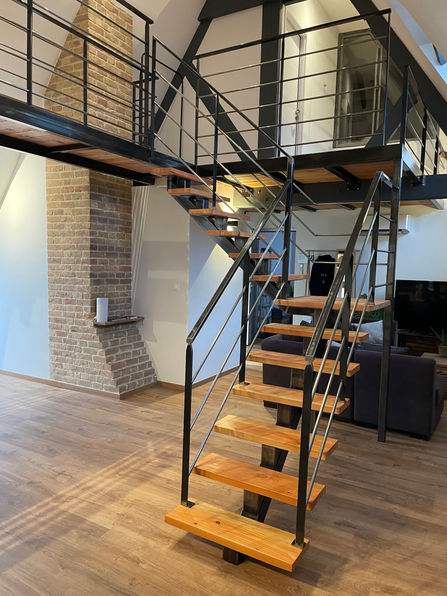 escalier 1/4 tournant à palier droit avec rampe, associant des marches en douglas à une structure métallique brut vernis et des garde-corps rampants s'intégrant avec élégance dans un logement atypique